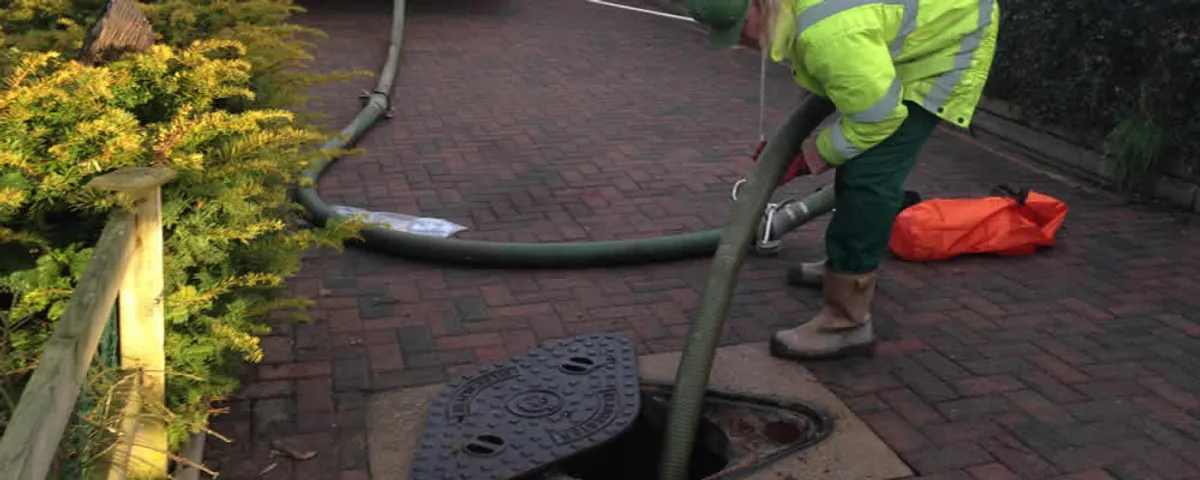 Septic tank cleaning technician servicing a septic tank with a vacuum hose in Staten Island, NY