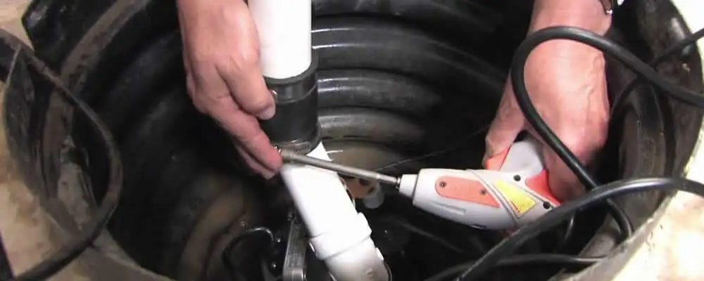 Sump pump installation technician connecting PVC discharge piping in Staten Island, NY
