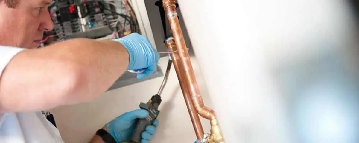 Water heater repair technician testing copper pipe connections and controls in Staten Island, NY